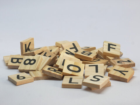 Pile of wooden squares with random letters, on a white background.