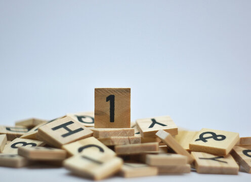 Number one on top of a pile of random wooden letters, on a white background.