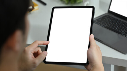 View over shoulder of man hands holding digital tablet and pointing with finger. Blank screen for webpage or advertise text
