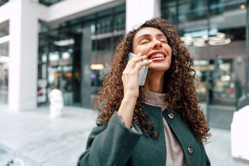 Young woman talking on mobile phone while walking in the city