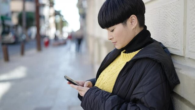 Young chinese woman smiling confident using smartphone at street