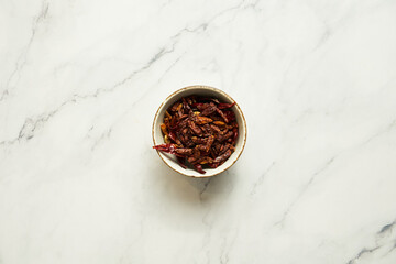 Roasted dry chili peppers in bowl on white background. Top view.