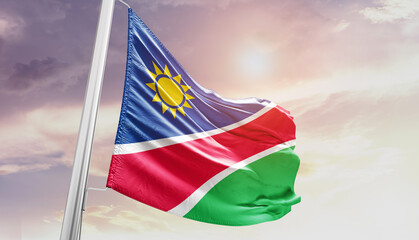 Waving Flag of Namibia in Blue Sky. The symbol of the state on wavy cotton fabric. - obrazy, fototapety, plakaty