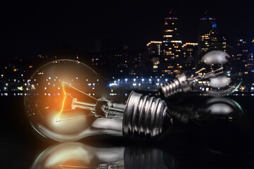 close up of tungsten light bulb with glow on dark background and night city lights