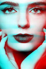 Obraz premium Studio portrait of beautiful woman with make-up and dark lips. Model looking at camera and holding cheeks with hands. Red and blue channel color split effect applied. Futuristic looking style
