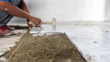 Tiler installing ceramic tiles on a floor. construction workers laying tile over concrete floor using tile levelers, notched trowels and tile marble.