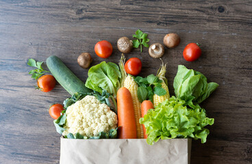 Shopping or delivery healthy food background. a fresh group of vegetables on wood background. burlap bag filled with vegetables and fruits , healthy eating and organic agriculture concept. - 575871597