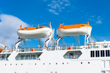 Two lifeboats of a passenger ship in an ocean under the blue sky.