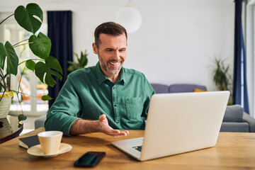 Man having video call sitting at desk using laptop