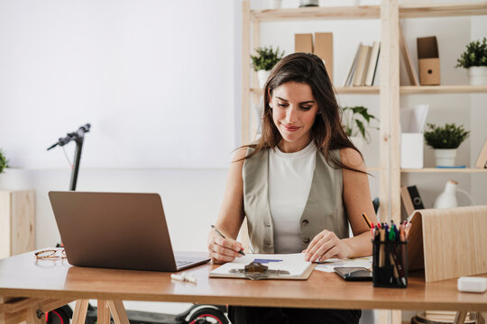Smiling businesswoman checking with documents in office