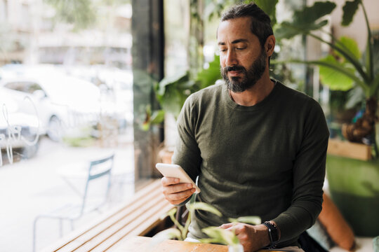 Mature man using mobile phone at cafe