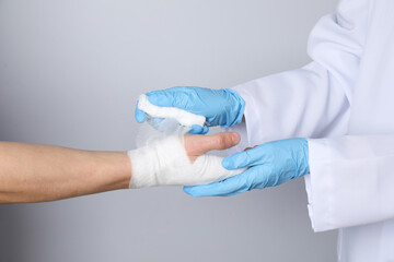 Concept of help during an injury, doctor wrapping hand in bandage on white background - obrazy, fototapety, plakaty