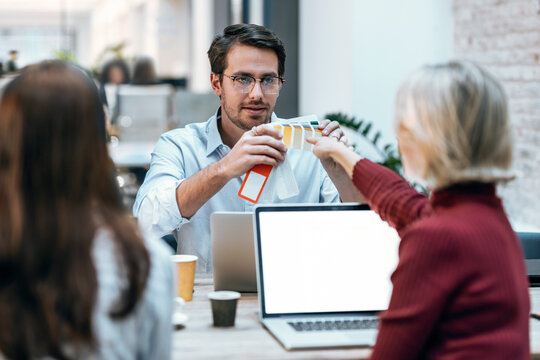 Design Professional With Colleague Discussing Over Color Swatches At Office