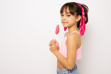 beautiful cute little child girl eating lollipop standing isolated over white background.