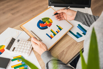 Hands of businessman examining pie charts and graphs at desk in office