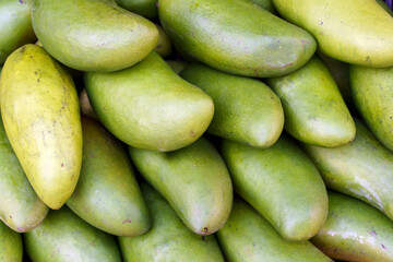 Ripe green mangoes at the fruit market. Harvest of exotic sweet mangoes and fruits. Selected focus