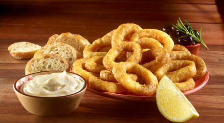 Frittierte Calamaris mit Baguette und Oliven auf einer Holzplatte