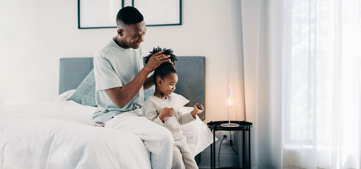 Black dad styling his daughter’s Afro hair at home