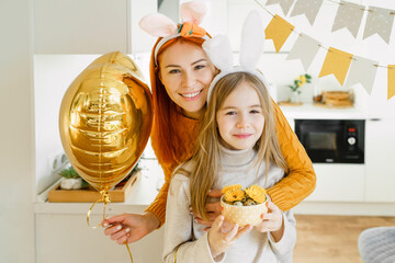 Happy girl with mother holding balloon celebrating Easter at home