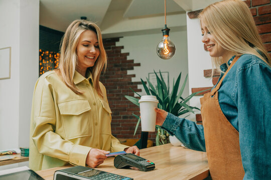 Smiling customer paying via tap to pay at coffee shop