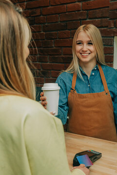Smiling owner giving coffee to customer at coffee shop