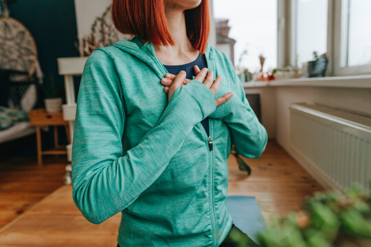 Woman with hands on chest doing breathing exercise at home
