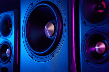 Two sound speakers and subwoofer on dark background with neon lights. Set for listening music....