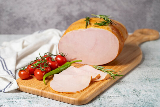 Smoked turkey meat sliced. Smoked turkey/ham fillets on a wood serving board. Deli products.