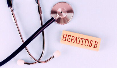 On a blue background, a stethoscope and wooden block with the word HEPATITIS B .Medical concept