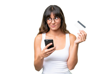 Young caucasian woman over isolated background buying with the mobile with a credit card while...
