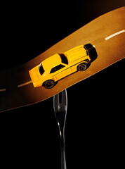 a metaphorical composition about a fork in the road, the fork holds the road along which the car is driving, consecrating the road with headlights
