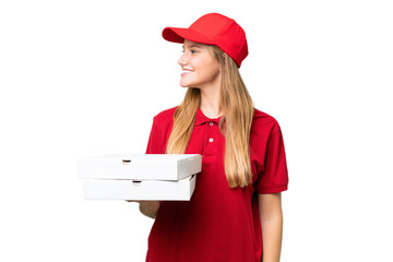 Young caucasian pizza delivery woman with work uniform picking up pizza boxes over isolated...