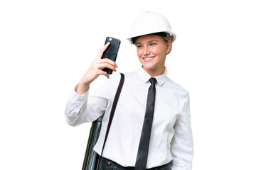 Young architect caucasian woman with helmet and holding blueprints over isolated background making a selfie