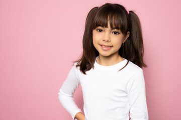 Portrait image with smiling little brown-haired girl. Concept happy and beauty kid with good healthy teeth for dental on pink background, eight year child looking at camera and posing