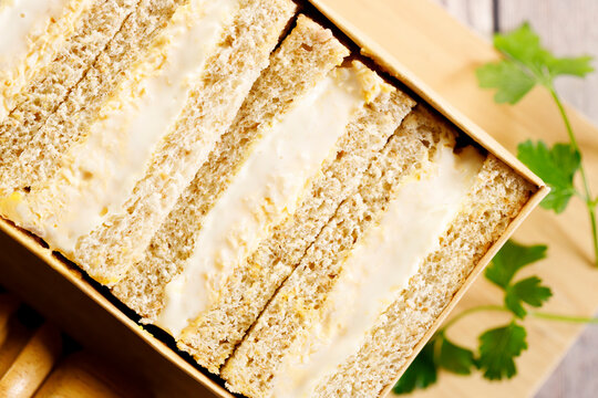 Egg salad sandwiches on wooden board.