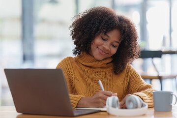 Young black African woman university student learning online using laptop computer. Smiling girl...