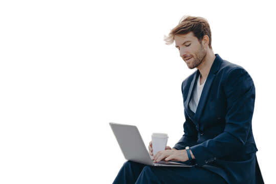 Businessman in formal suit reads news via laptop computer works online drinks takeaway coffee