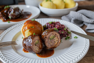 Beef Roulades with gravy, red cabbage and potato dumplings on a plate.