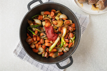 Roasted root vegetables or mirepoix with tomato paste in a roasting pan for cooking sauce or gravy for german beef roulades. Cooking, preparation, making. Part of a series
