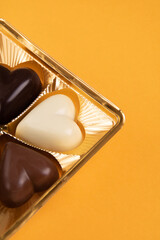 photo chocolates in the shape of hearts lying in a package on a yellow background