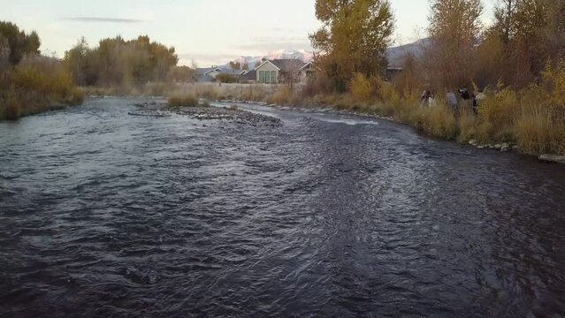 rushing rocky creek at sunrise with golden fall colors in a residential neighborhood in Heber Utah - AERIAL DOLLY REVERSE TILT