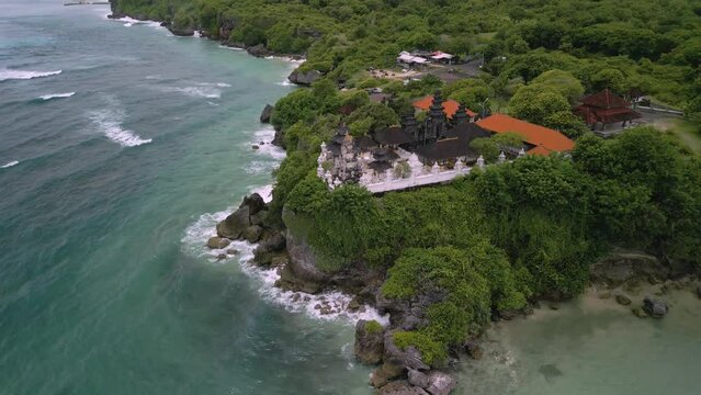 Drone panning shot of a giant temple complex between the green nature on a cliff