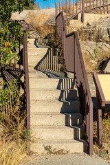 Cement stairs in park or look out point with metal hand rails in natural setting with rusted and red exterior with grass