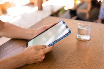 Young man hands with mock up display tablet and wooden desk