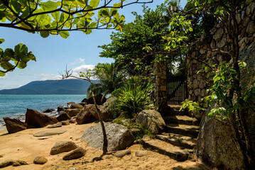 View of idyllic beach under shade in corner with idyllic entrance to local house, Ilhabela, São Paulo