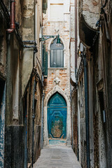 Venice Italy old antique buildings in warm yellow and sand tones with green, teal and turquoise doors and windows.