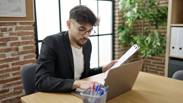 Young arab man business worker using laptop reading document at office