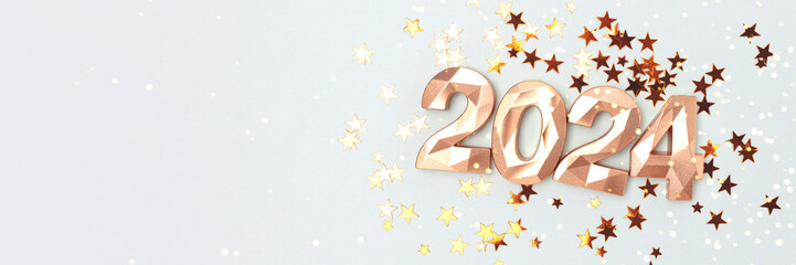 Banner with 2024 gold colored numbers and glowing stars confetti on a blue background. New Year...