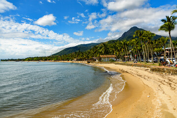 Side view of empty beach, mountains and palm trees on the waterfront in Ilhabela, São Paulo