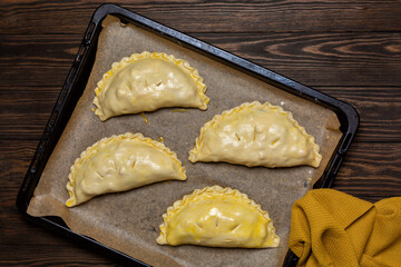 Cooking meat turnovers or pies, or empanadas, or cornish pasty. Unbaked, raw food, egg washed, on a baking tray.